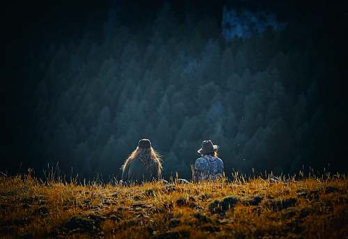 challis man and woman sitting on brown field flora